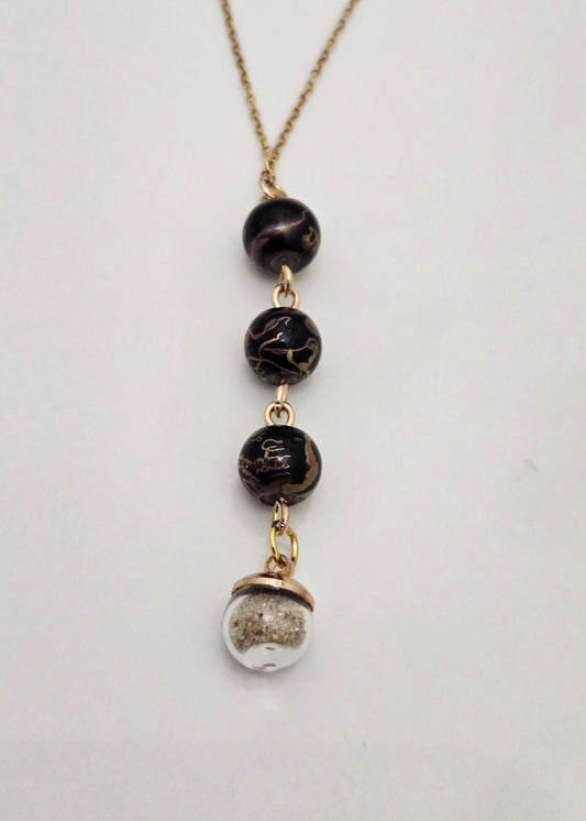 Collier noir et doré, sable de plage