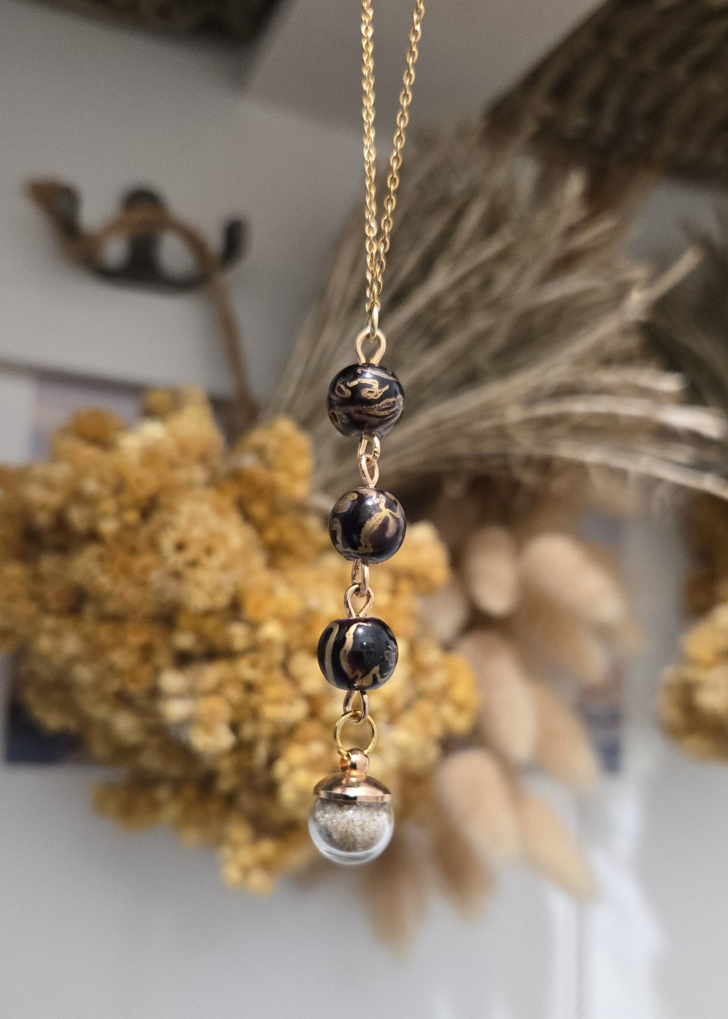 Collier noir et doré, sable de plage