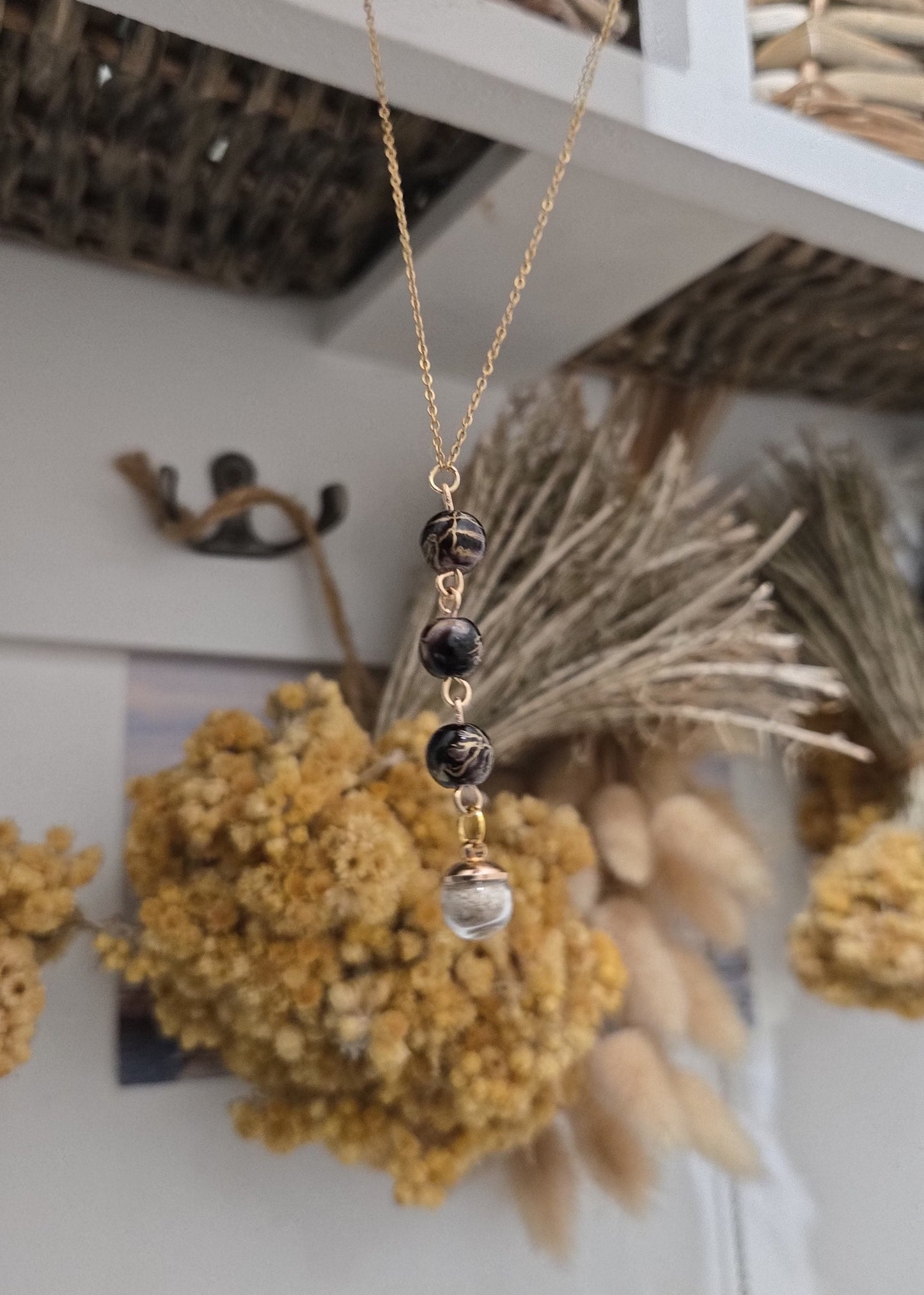 Collier noir et doré, sable de plage