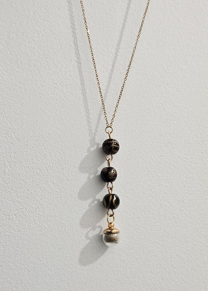 Collier noir et doré, sable de plage