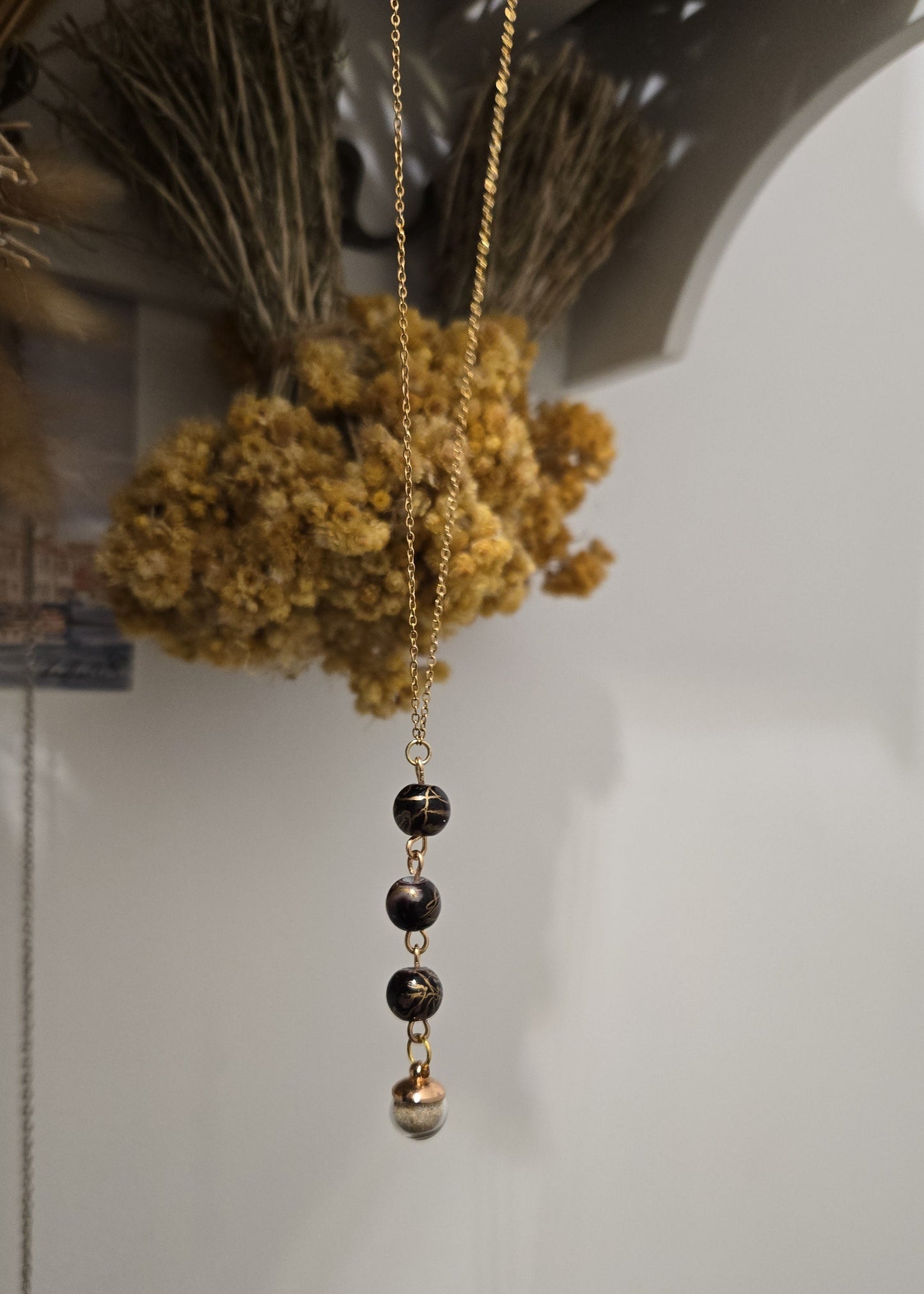 Collier noir et doré, sable de plage