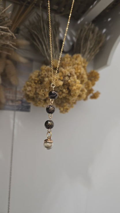 Collier noir et doré, sable de plage